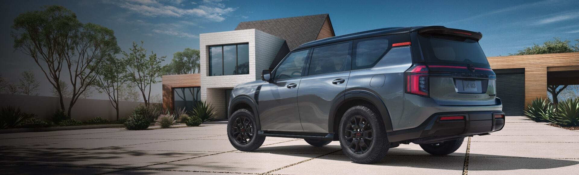 Rear side view of 2026 Nissan Armada parked in front of modern house